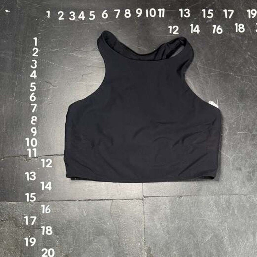 Black tank top on a gray floor with measurement markings