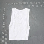 White tank top on a gray textured background with measurement scale