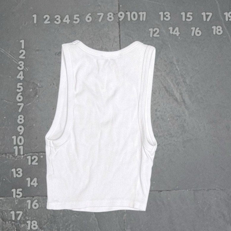 White tank top on a gray textured background with measurement scale
