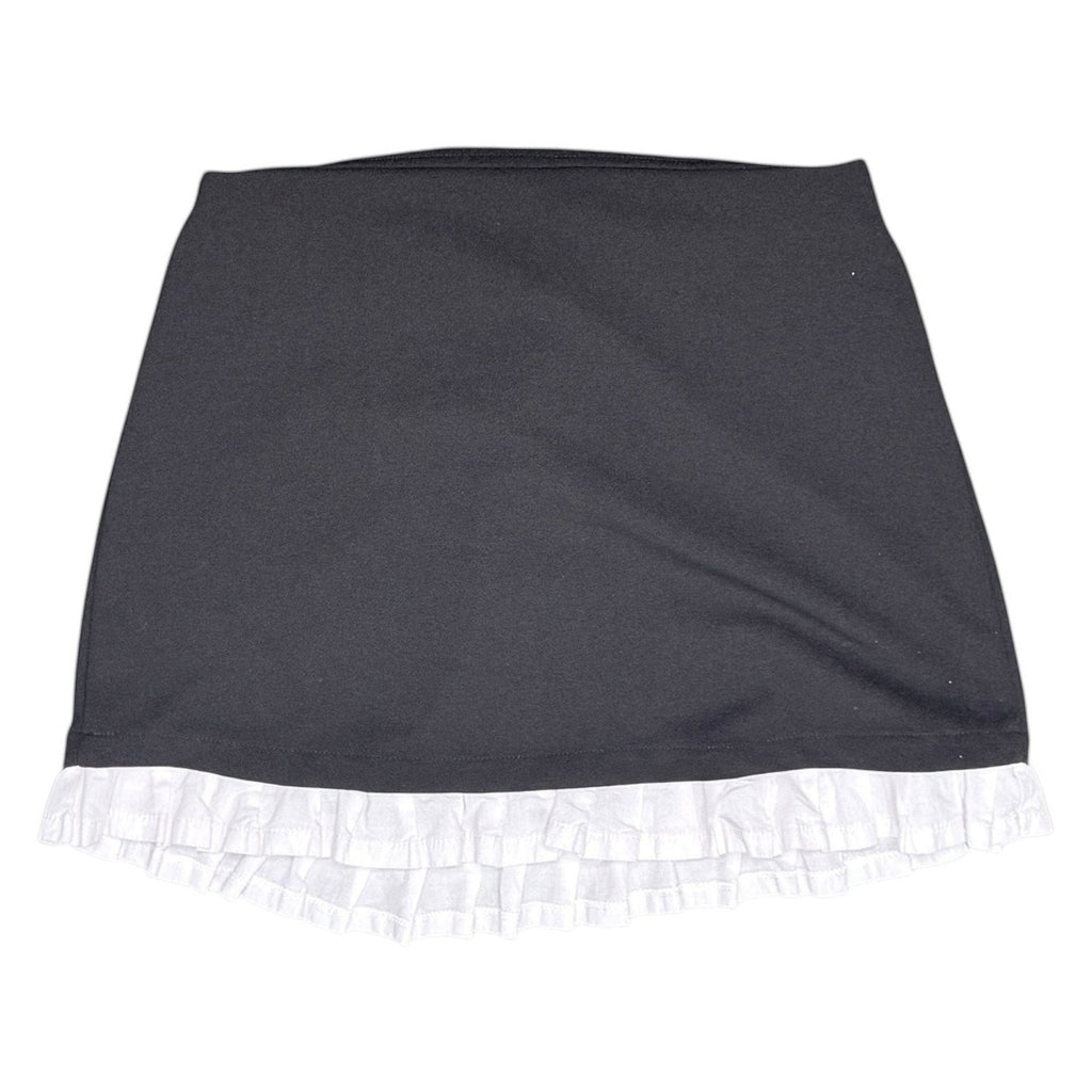 The Room Collective black mini skirt with white ruffled hem. High-waisted, slim fit, stretchy polyester/spandex blend with cotton ruffle.
