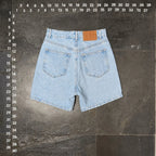 The Room Collective light wash denim shorts with five-pocket styling and a brown leather patch.
