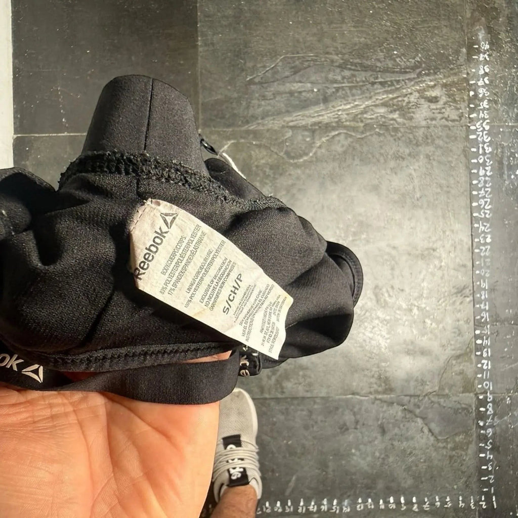 The Room Collective Reebok black logo strap sports bra, size S. Racerback design with polyester-spandex blend.