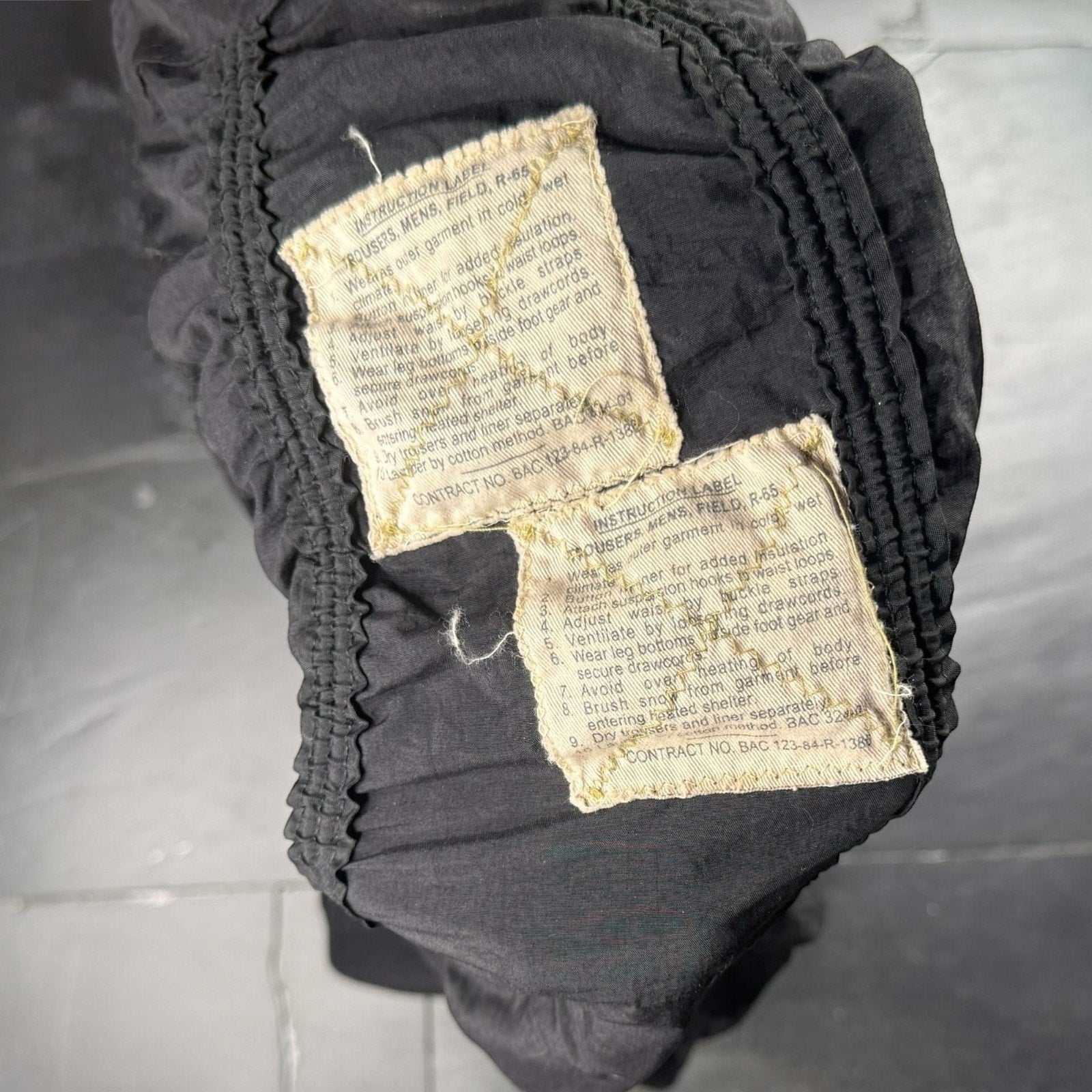 The Room Collective Riley black ruched nylon parachute skirt with vintage instruction labels and drawstring hem. Size S.