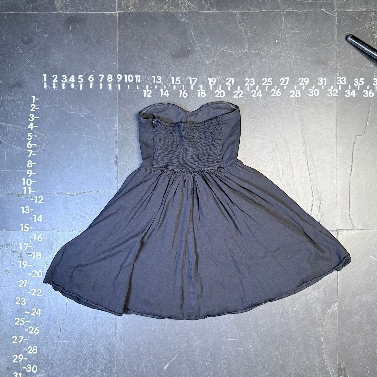 The Room Collective black strapless sweetheart mini dress with shirred back and flared skirt.
