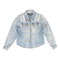 The Room Collective light wash denim trucker jacket with distressed cuffs and hem, featuring dual chest pockets and gold-tone buttons.